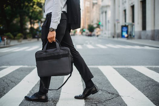 Professional businessman walking across city street with briefcase, wearing formal attire.